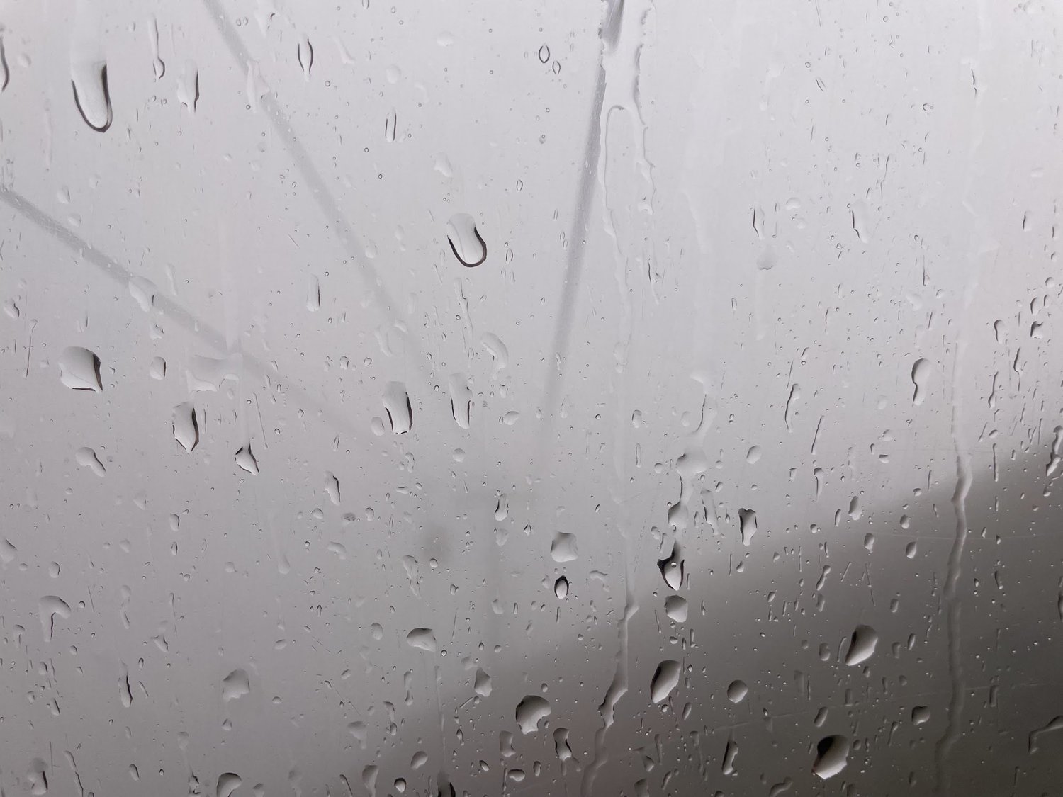 Rain droplets and streaks scattered across a pane of glass